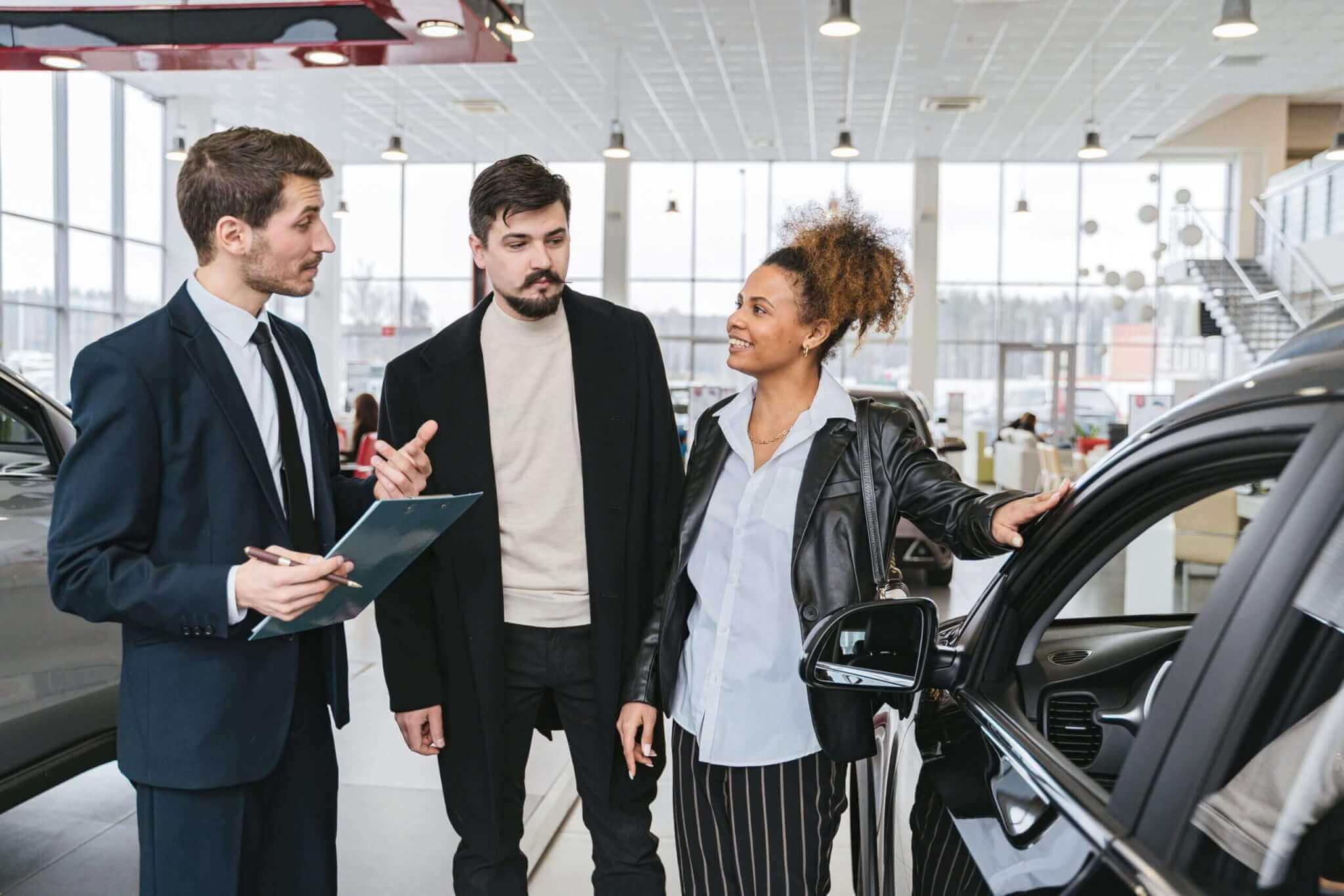 Venditore auto con due clienti in concessionario